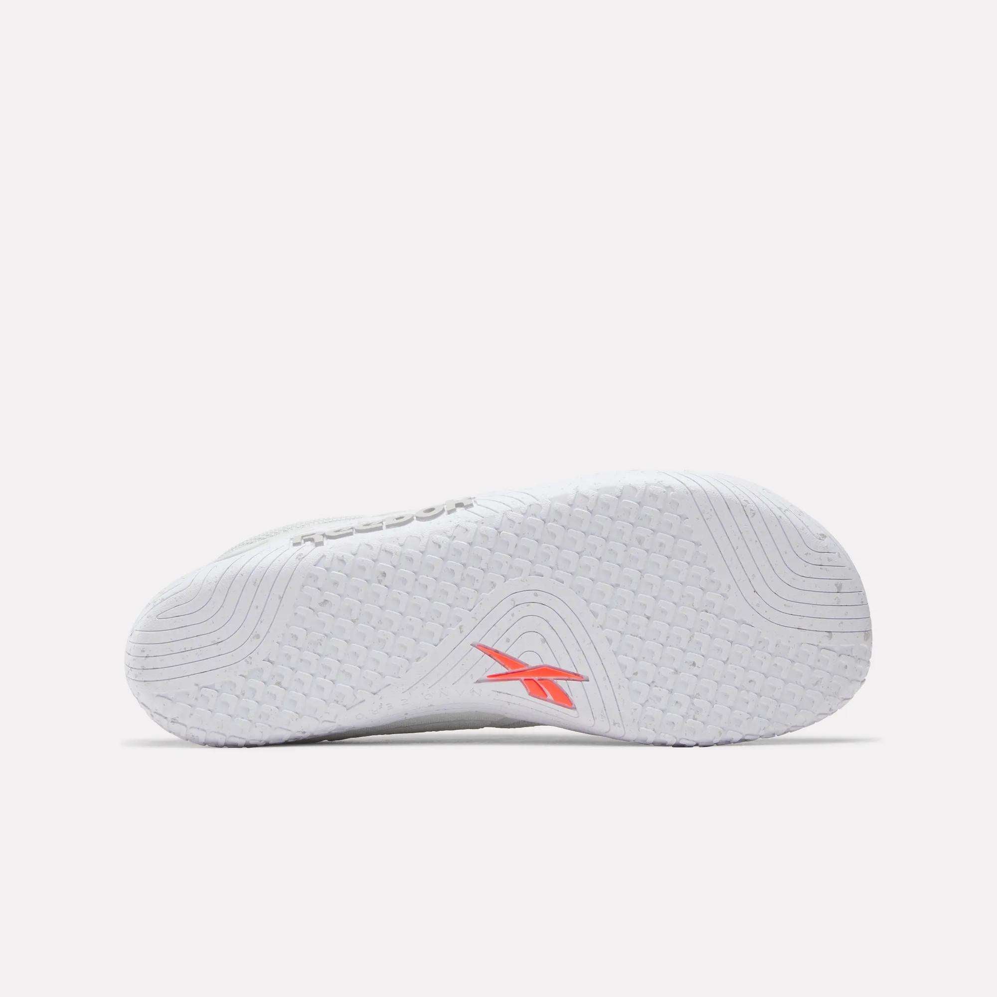 The image shows the white sole of Reebok Nano Zero Training Shoes, featuring textured grip patterns and a red Reebok logo near the arch. The background is plain and light.