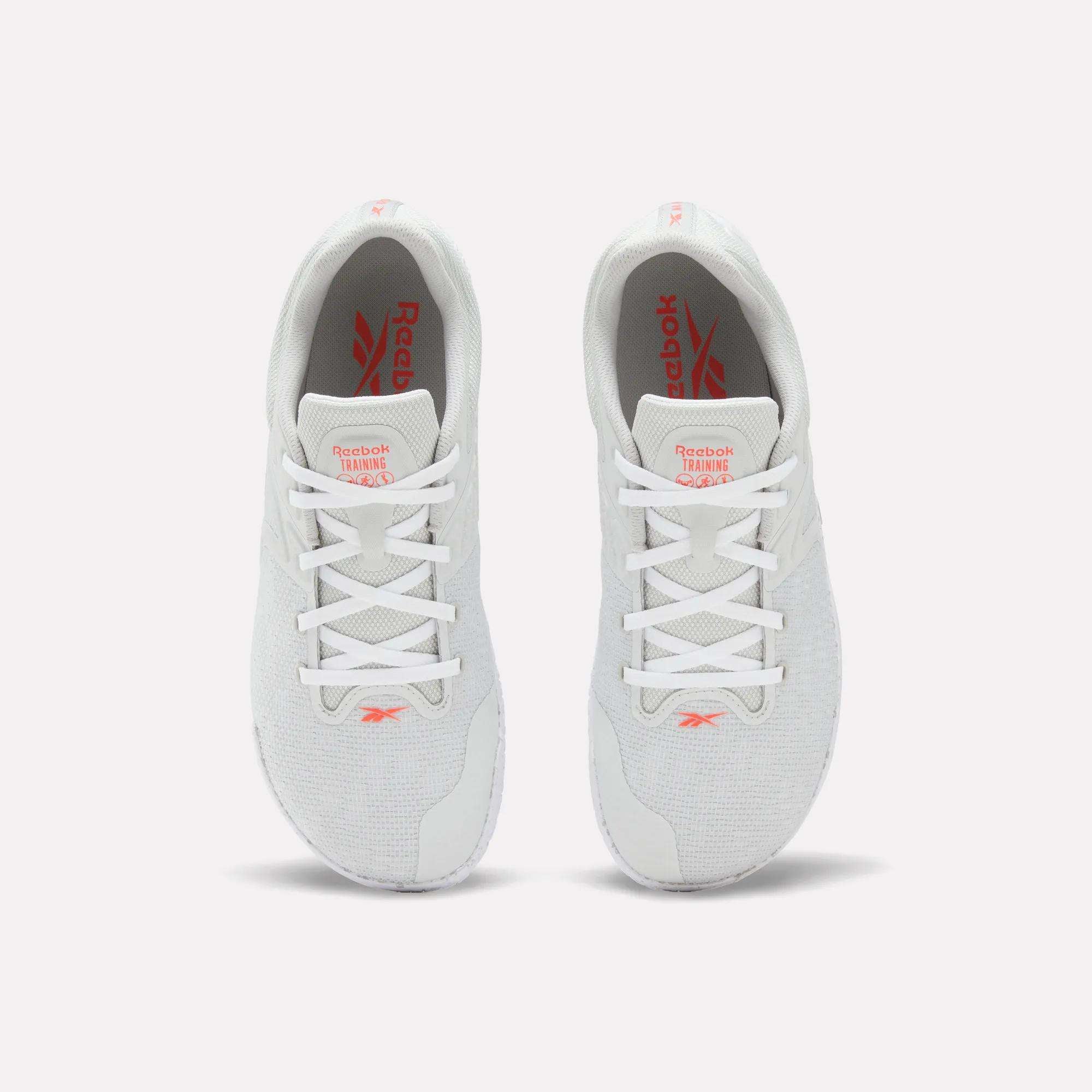 A pair of white Reebok Nano Zero Training Shoes, shown from above on a plain white background, feature red Reebok branding on the tongue and insole, white laces, a breathable mesh upper, and a zero-drop design.