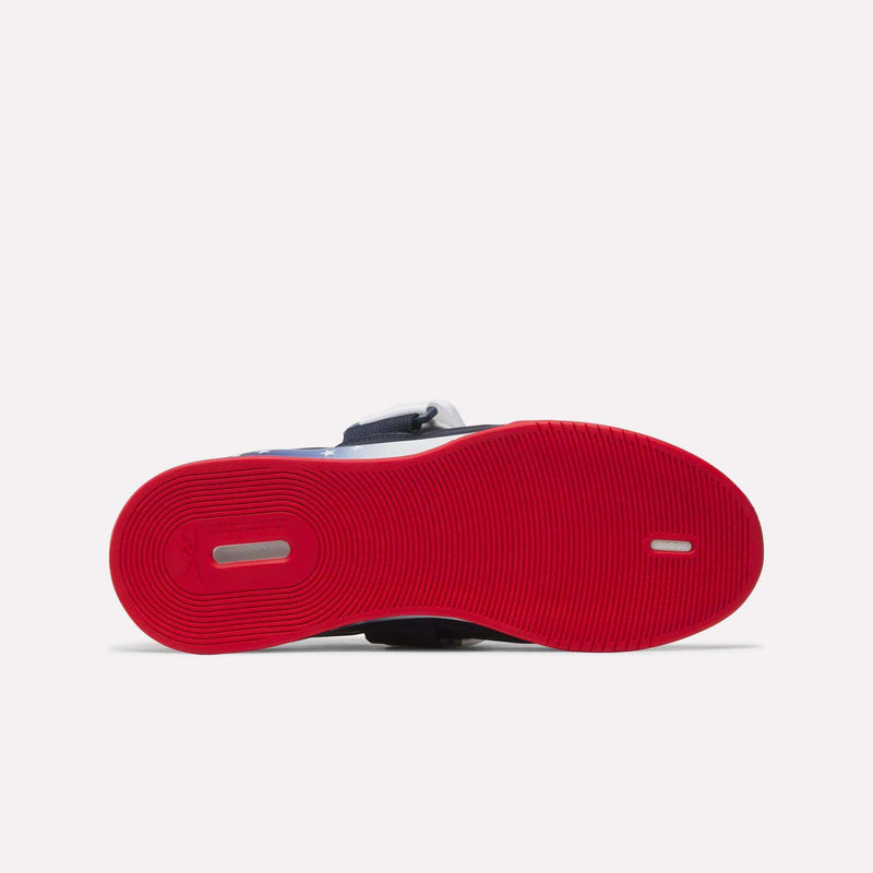 A bottom view of the Reebok Men's Legacy Lifter IV Shoes shows a bright red ridged sole for stability, featuring a small oval cutout and logo near the heel. The upper part of the shoe is partially visible above the sole.