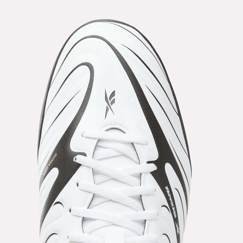 Close-up of the Reebok Sidewinder 26 League Turf Cleats—a white athletic soccer shoe with black curved stripes and white laces, viewed from above. Specially designed for turf players, these cleats feature a modern, sporty look ideal for artificial soccer fields, with a visible Reebok logo on the tongue area.