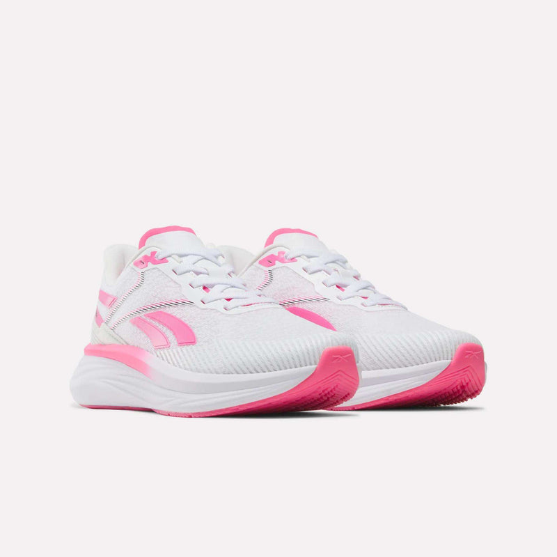 A pair of Women’s Viva Speed Shoes by Reebok in white, featuring vibrant pink accents on the soles, sides, and laces, displayed against a plain white background. These breathable shoes offer athletic style and comfort for all-day wear.