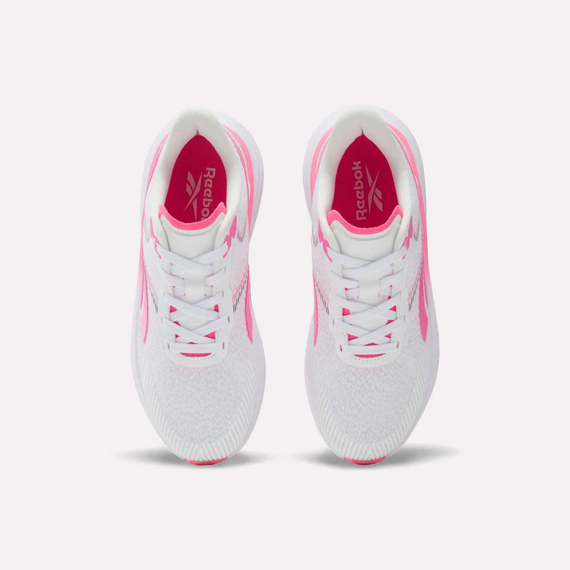 Top view of a pair of Reebok Women’s Viva Speed Shoes in white with pink accents, showcasing cushioned soles designed for all-day comfort. The image highlights the laces, interior logo, and textured soles. These breathable shoes are displayed side by side against a plain white background.