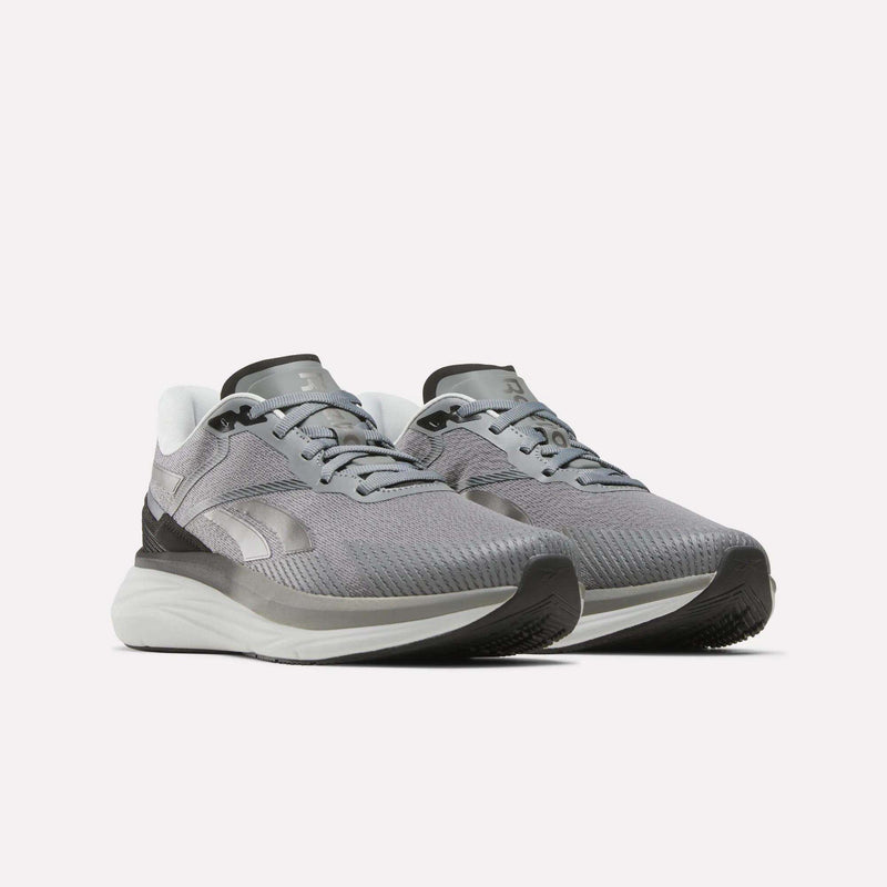 A pair of Reebok Men's Viva Speed Shoes in gray and white, featuring mesh uppers, cushioned white soles, and black accents, are displayed on a plain white background. These breathable shoes offer enhanced comfort with their cushioned soles, making them ideal for athletic activities.