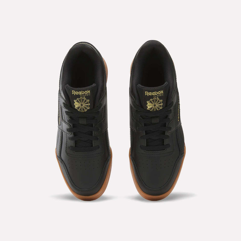 Top view of Reebok Workout Plus Shoes for big kids in black with brown gum soles, gold branding, and a star logo on the tongue, side by side on a white background—a sporty pick for juniors.