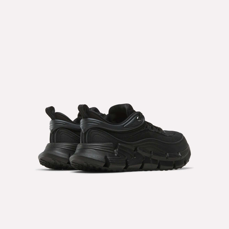 A pair of black Reebok Floatzig Encore Running Shoes with chunky soles are positioned at an angle, displaying both the back and side views against a plain white background. Ideal for walking and fitness enthusiasts, these running shoes feature innovative Zig tech soles for enhanced comfort and support.