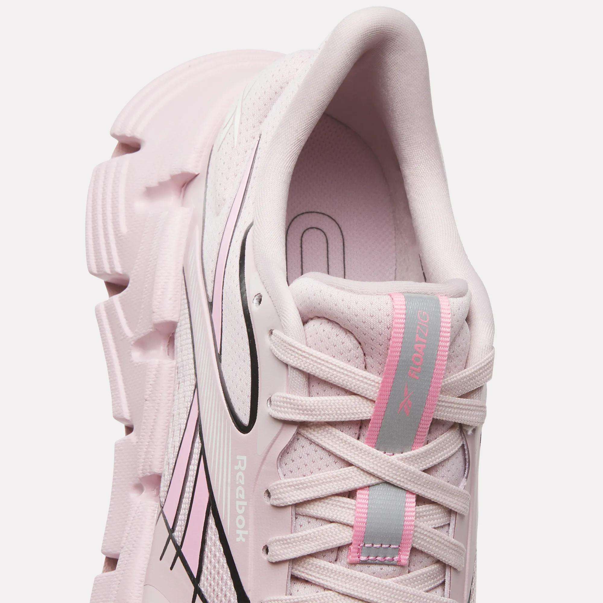 A close-up top view of the Reebok Women's FloatZig 2 Running Shoes in light pink, featuring chunky textured soles, black accents, a pink and gray tongue, Superfloat+ cushioning, breathable mesh, and white laces for comfort on your run.