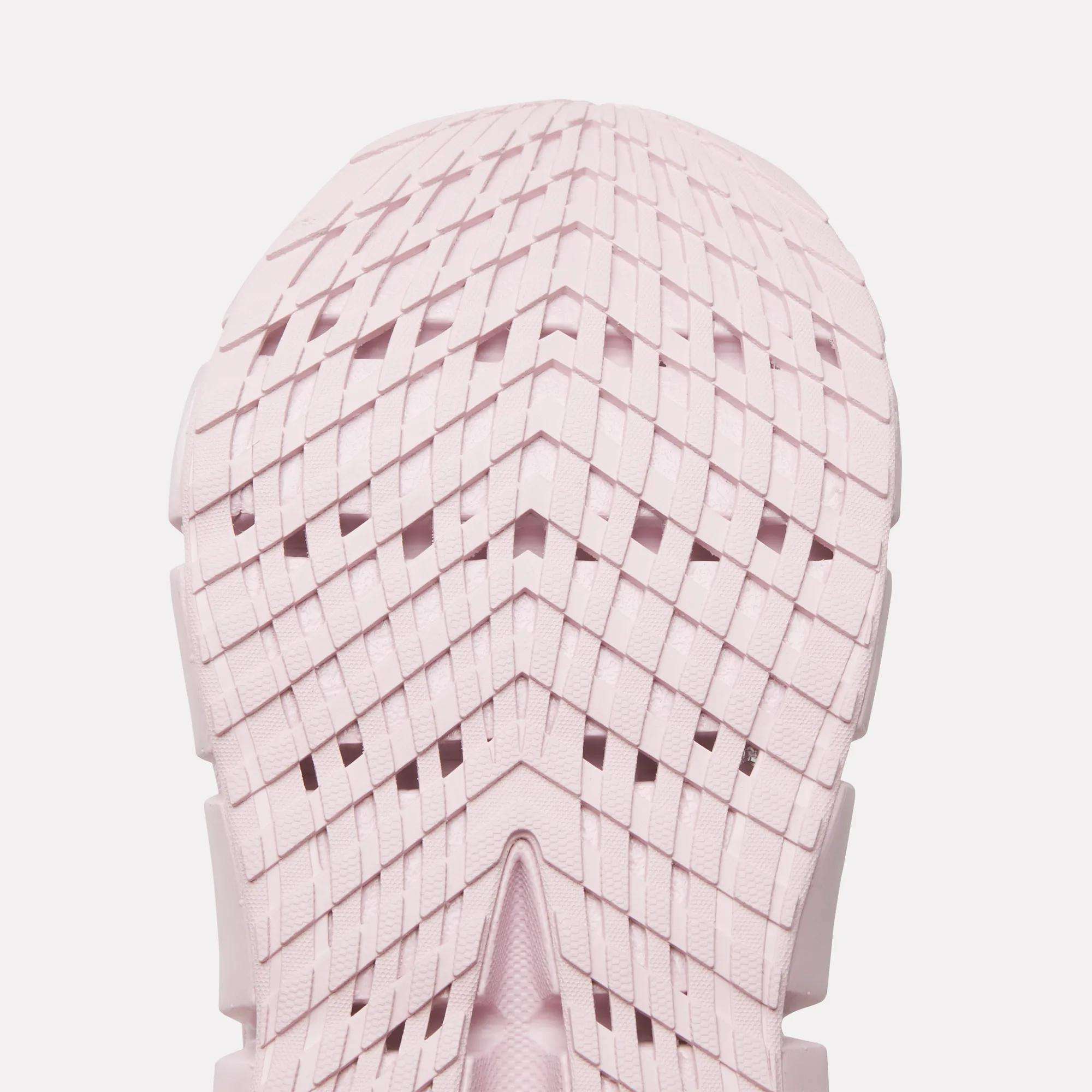 Close-up of a light pink Reebok Women's FloatZig 2 Running Shoe sole, featuring a geometric grid tread with chevron shapes and intersecting lines. The symmetrical design showcases Superfloat+ cushioning for a springy run.