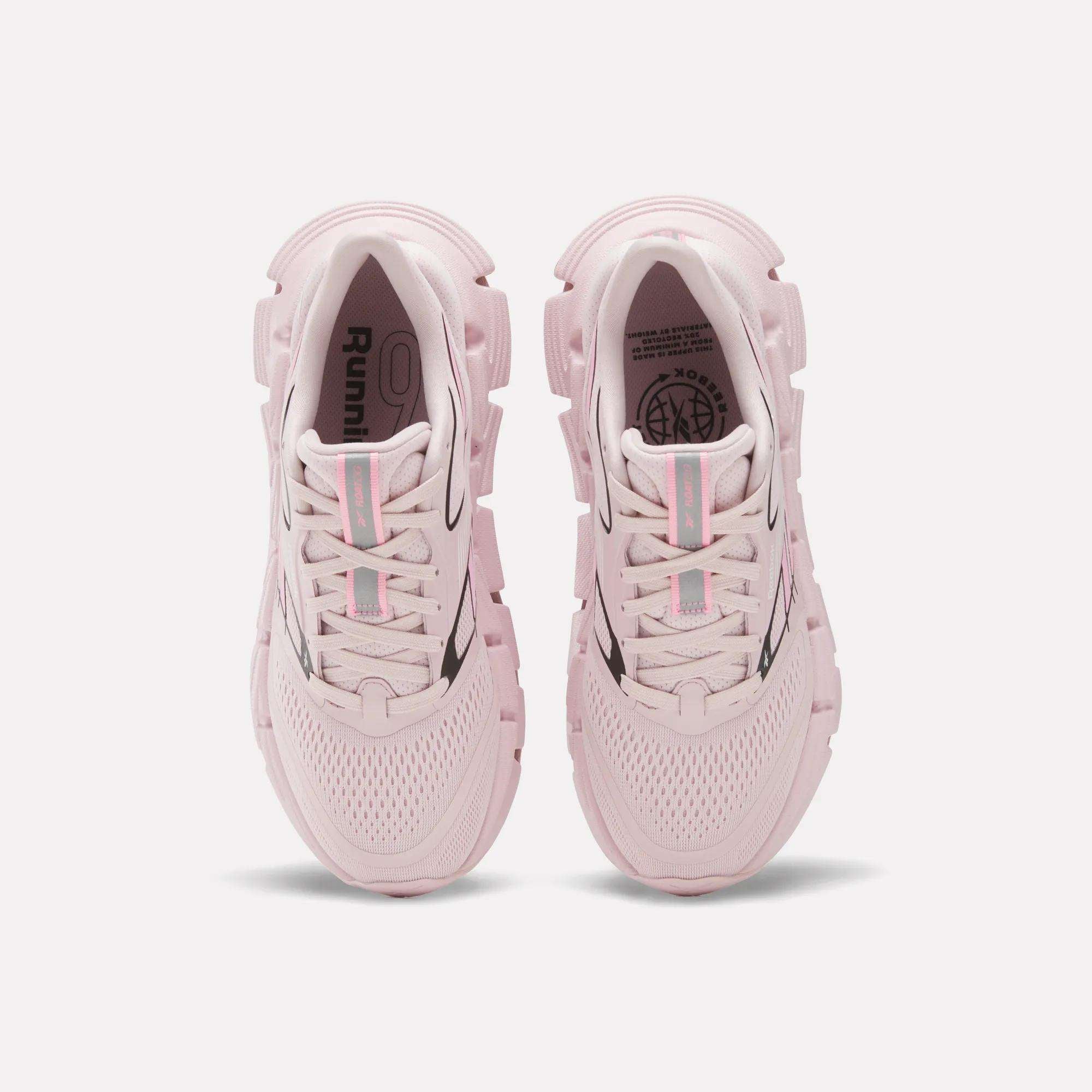 A pair of Women's FloatZig 2 Running Shoes by Reebok in light pink, seen from above with mesh uppers, chunky soles with Superfloat+ cushioning, and light blue and pink striped laces, displayed on a white background.