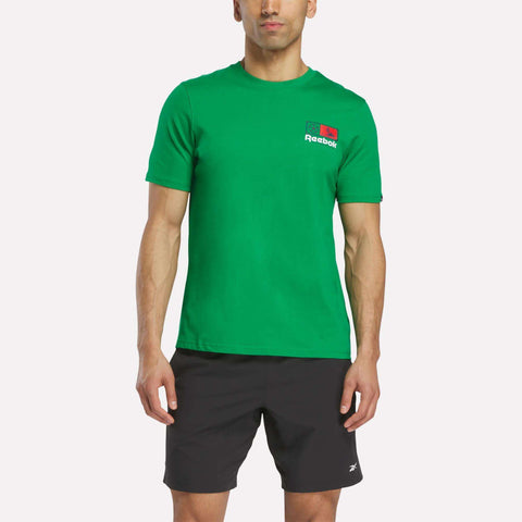 A man in a green Reebok Mexico Football T-Shirt and black shorts stands facing forward against a plain white background.