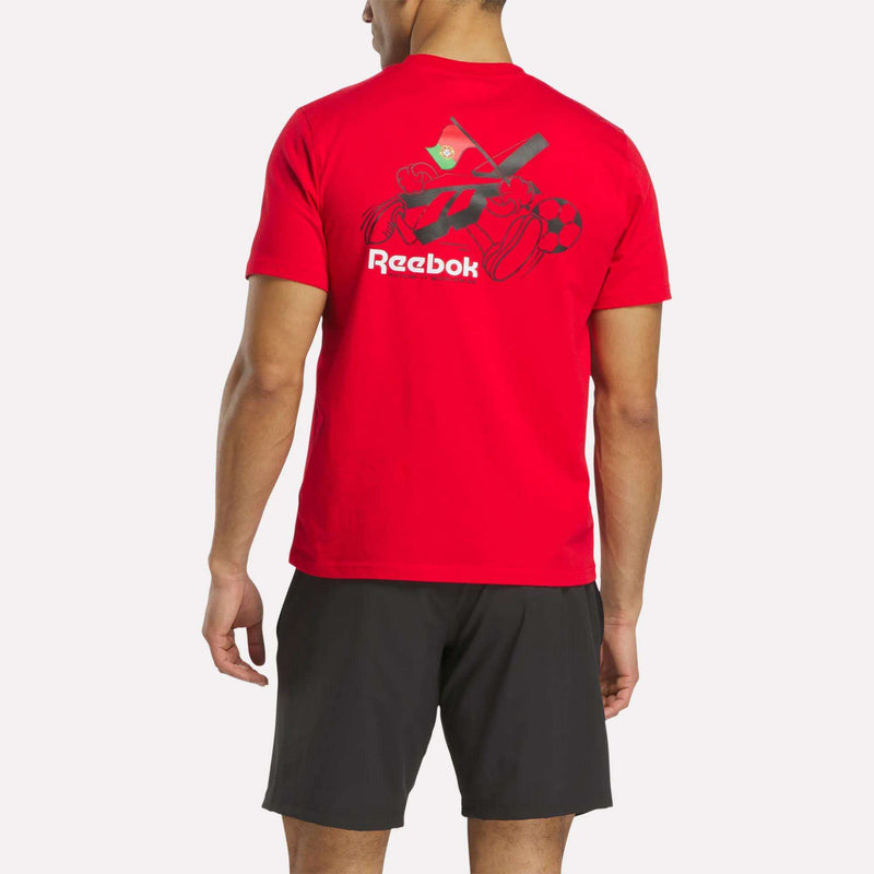 A man in a red Reebok Portugal Football T-Shirt with team graphics on the back and black shorts stands facing away from the camera against a plain white background.