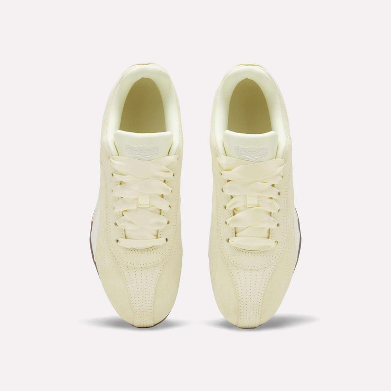 Two cream-colored Women’s Ultra Lo Shoes by Reebok, shown from above, showcase a suede upper, classic laces, rounded toes, and perforated details on the toe area, all set against a plain white background.