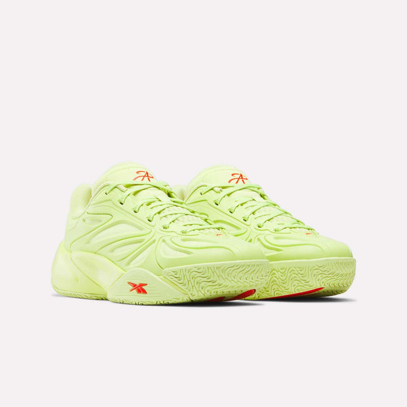 Two light green Angel Reese 1 Shoes for big kids by Reebok, with textured soles and orange logos, are placed side by side. Their modern, sculpted basketball style pops against a plain white background.