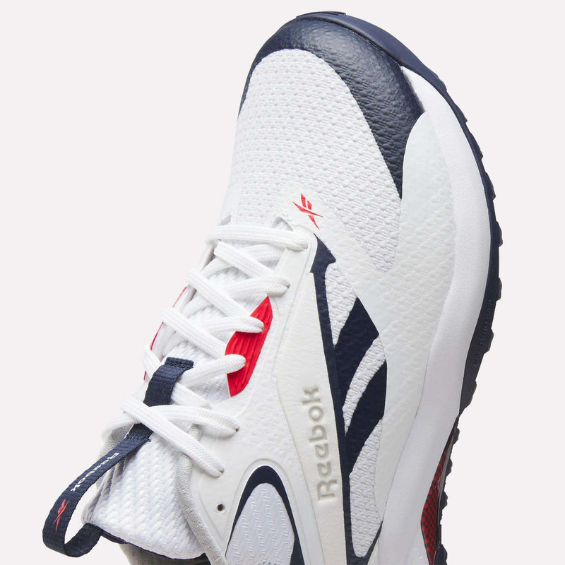 Close-up of Reebok Nano Golf Shoes in white with navy and red accents, featuring a FlexWeave upper, textured mesh material, patterned side panel, white laces, dark textured outsole, and signature Reebok branding.