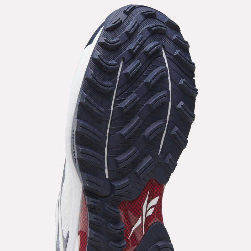 Close-up of the Nano Golf Shoes by Reebok, showing a rugged, textured dark blue sole with red and white accents, enhanced by Floatride foam cushioning and a Reebok logo near the heel.