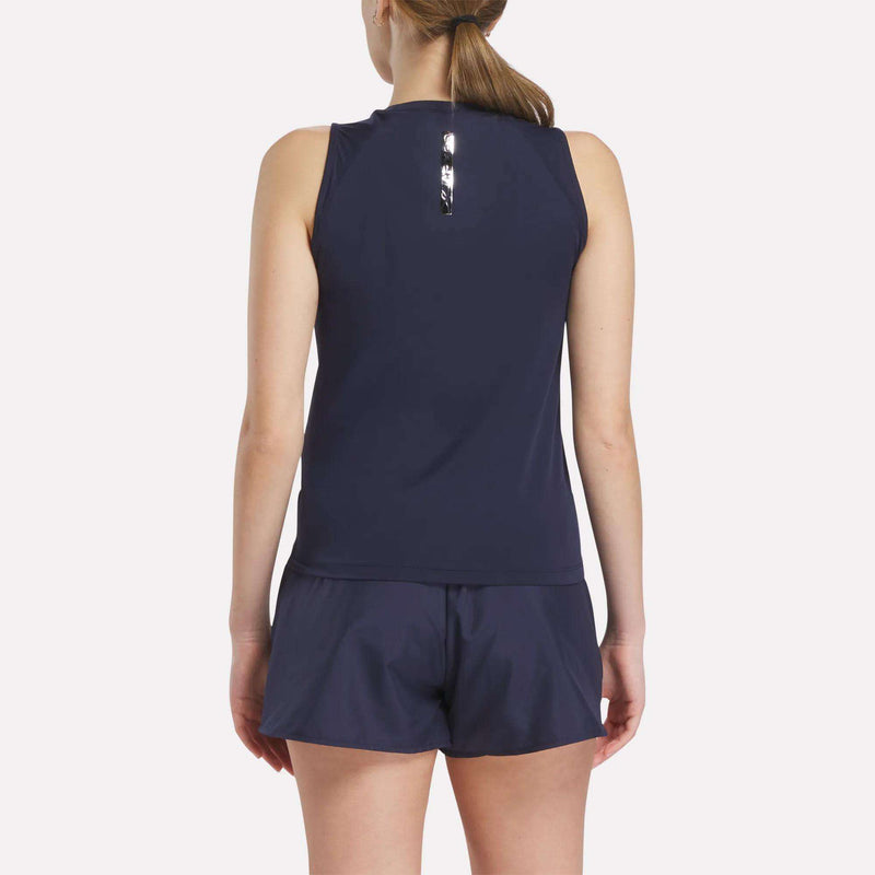 A woman with light skin and brown hair in a ponytail is seen from the back, wearing a Reebok Women's Reebok x F45 Training Coach Tank Top in navy with matching shorts, perfect for F45 Training, against a plain light background.