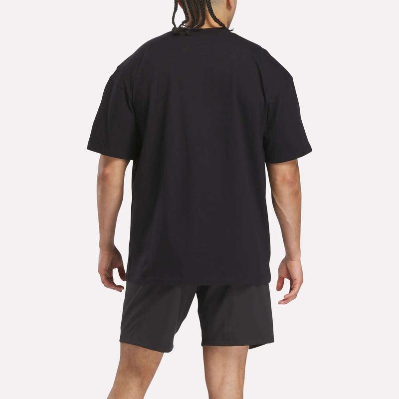 A person with braided hair, seen from behind, wears a Reebok x F45 Training Relaxed T-Shirt and black shorts against a plain light background.