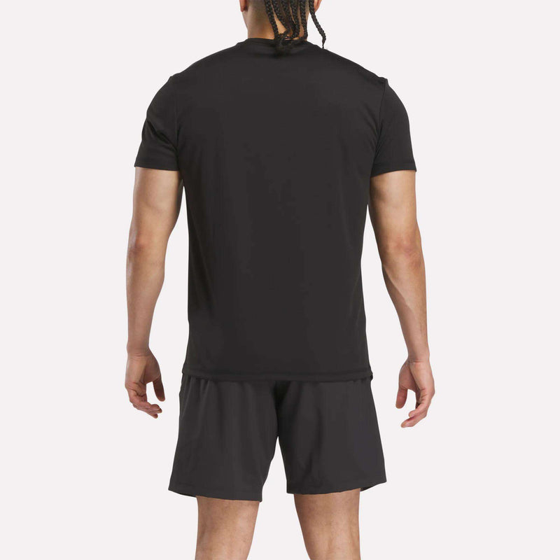 A person stands facing away from the camera, wearing a Reebok Men’s Reebok x F45 Training T-Shirt and black shorts against a plain white background.