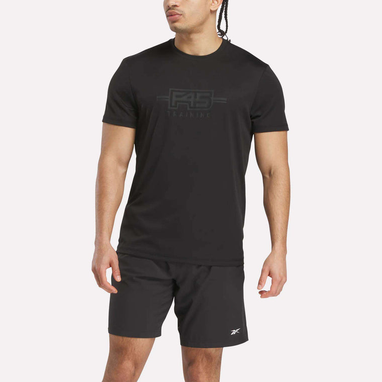 A person in a black Reebok x F45 Training Men's T-Shirt stands slightly sideways against a plain light background.