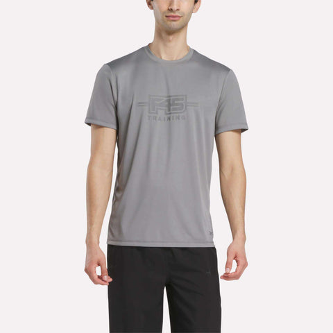 A man wears the Reebok Men's Reebok x F45 Training T-Shirt in Grey 3, featuring performance design and "RS TRAINING" print on the front, paired with black pants and standing against a plain white background.