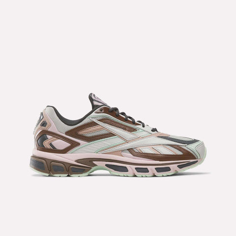 Introducing the Reebok Premier Road Ultra SV Shoes, a stylish sneaker inspired by Y2K footwear. Showcased in Elemental Pink, Almost Black, and Rosewood panels, this design features a chunky sole, mesh accents, and geometric patterns reminiscent of classic Reebok aesthetics. Displayed in a side profile against a plain white background.