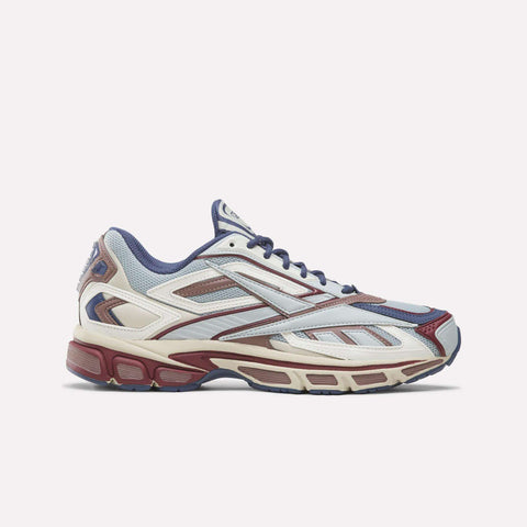 Introducing the Reebok Premier Road Ultra SV Shoes—a stylish athletic sneaker inspired by Y2K designs. This pair features a mesh and synthetic upper in Legacy Blue, Linen, and Light Cocoa hues with lace-up closure and a chunky sole. Photographed from the side on a plain background.
