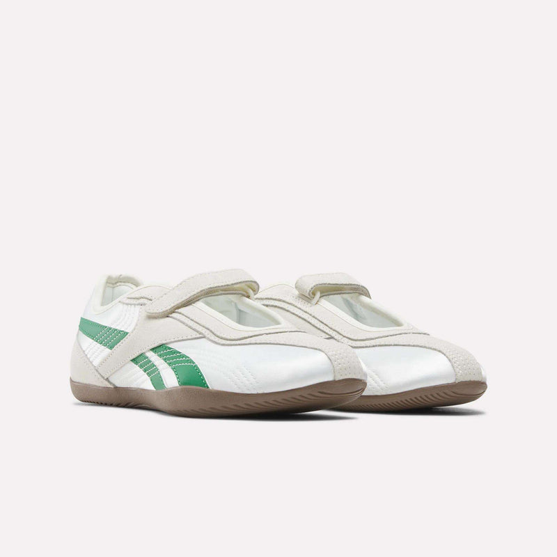 A pair of Women’s Ultra Lo Mary Jane Shoes by Reebok, featuring white uppers with light beige Velcro straps, green side stripes, and brown rubber soles, displayed on a plain white background.