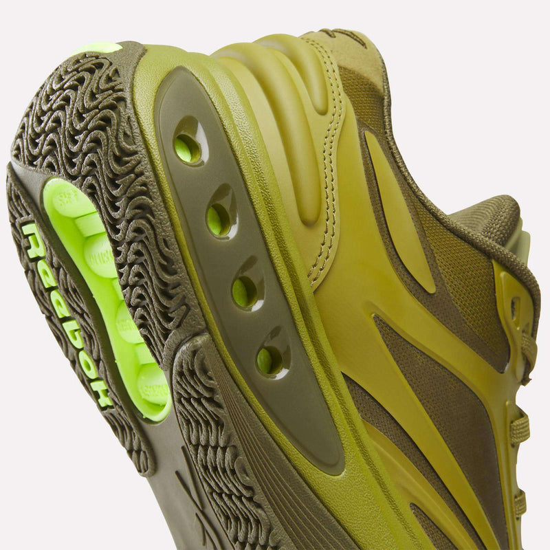 Close-up of an olive green Reebok Engine A Pump Shoes, highlighting the textured rubber sole with a bright green Pump technology mechanism visible through cutouts.