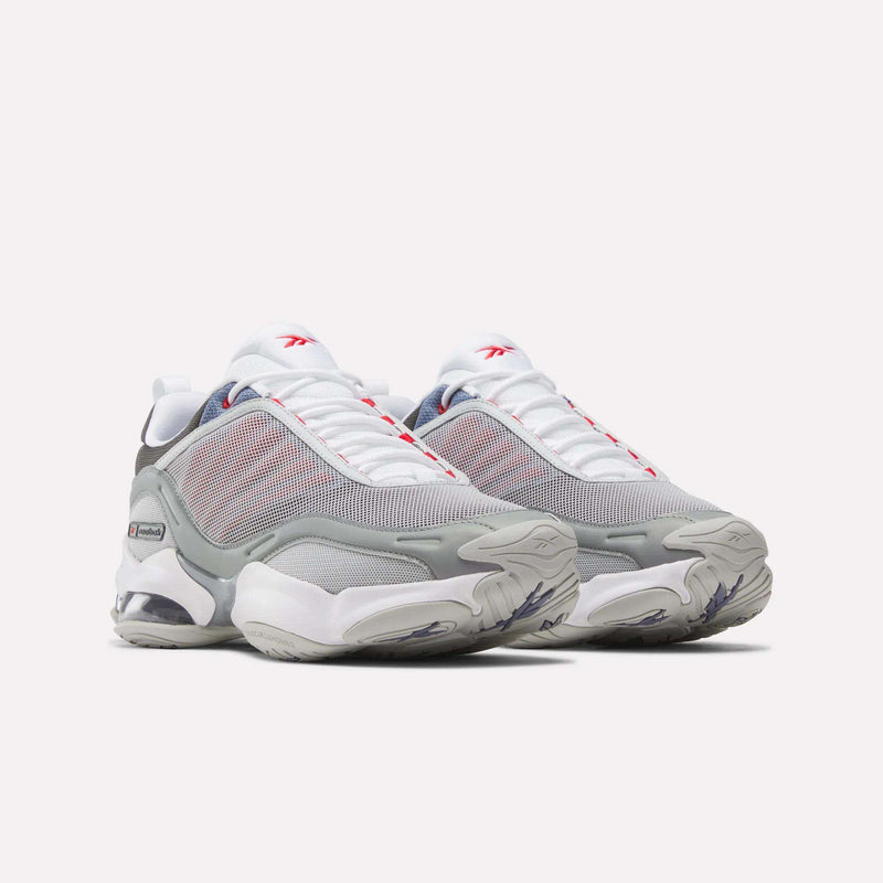 A pair of Reebok DMX Series 3000 Shoes in white, gray, and red with mesh uppers, chunky soles featuring DMX moving air technology for enhanced comfort, and prominent Reebok branding, displayed side by side on a light background.