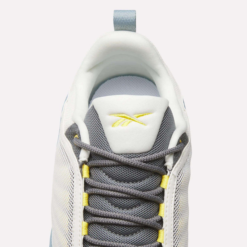 Top view of Reebok DMX Series 3000 Shoes in white and grey with yellow accents, dark grey laces, DMX moving air technology for comfort, and a yellow Reebok logo on the tongue, set against a light background.