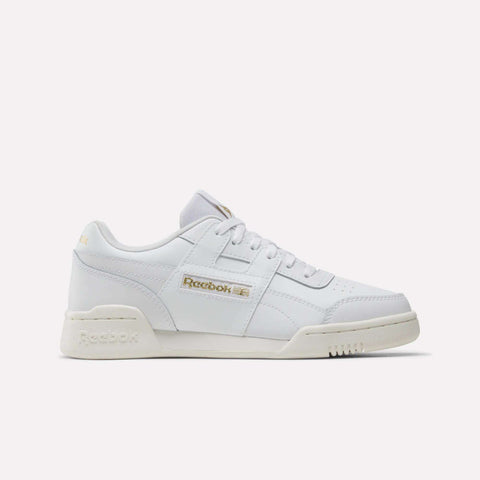 The Reebok Workout Plus Shoes - Big Kids are white low-top sneakers with gold branding on the side and heel, white laces, and an off-white sole—ideal sporty footwear for juniors, shown on a plain white background.