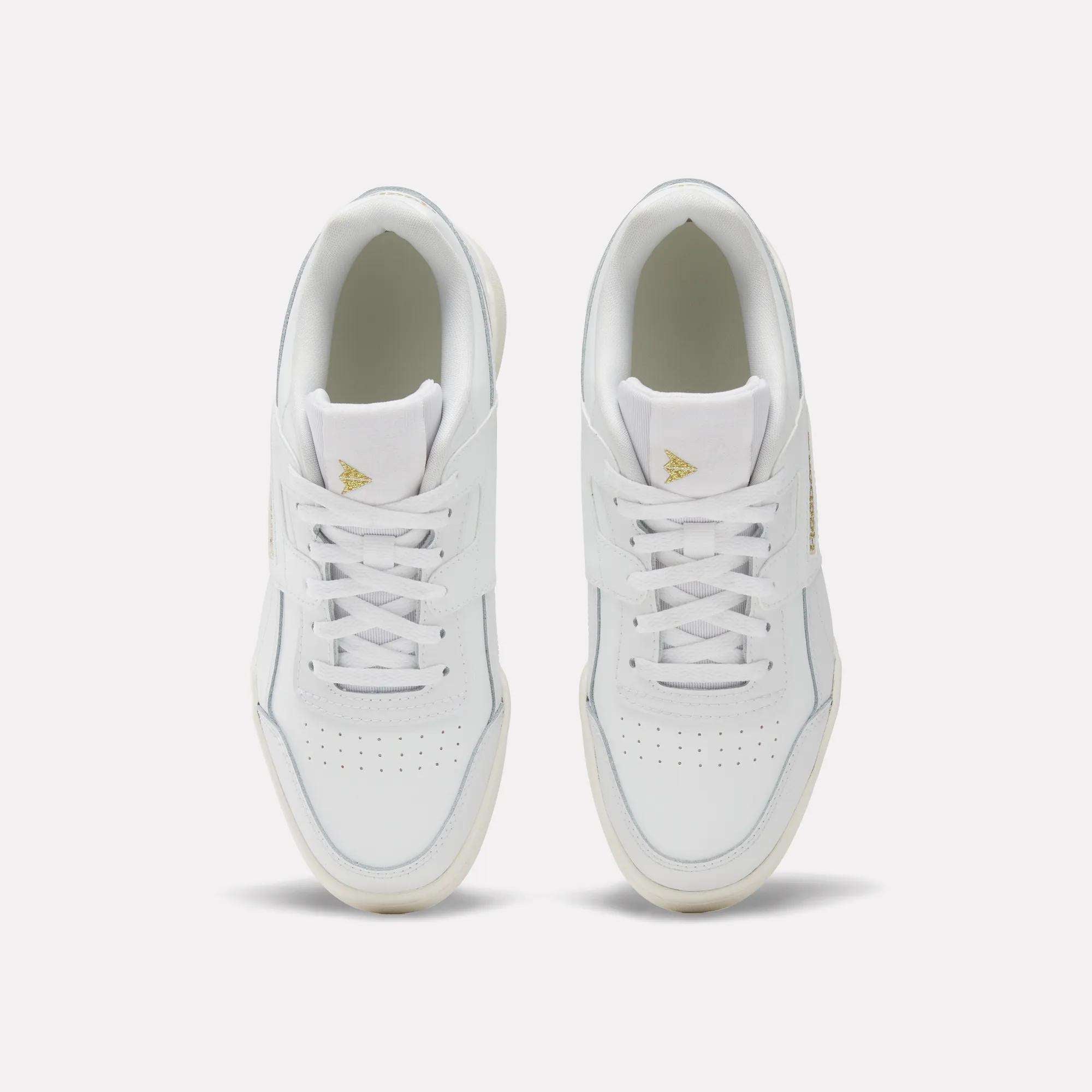 A pair of Reebok Workout Plus Shoes for big kids with laces, seen from above on a light background. These sporty white sneakers have perforated toe boxes and gold triangle logos on the tongues—ideal for juniors who want style and comfort.