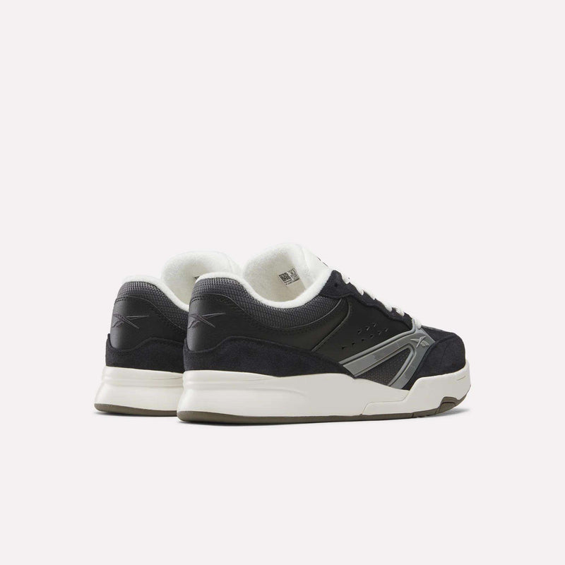 A pair of Reebok Omni Edge Shoes in black and white, designed with hoops-inspired style and crafted from premium materials, featuring white soles and shown from the back and side against a plain white background.