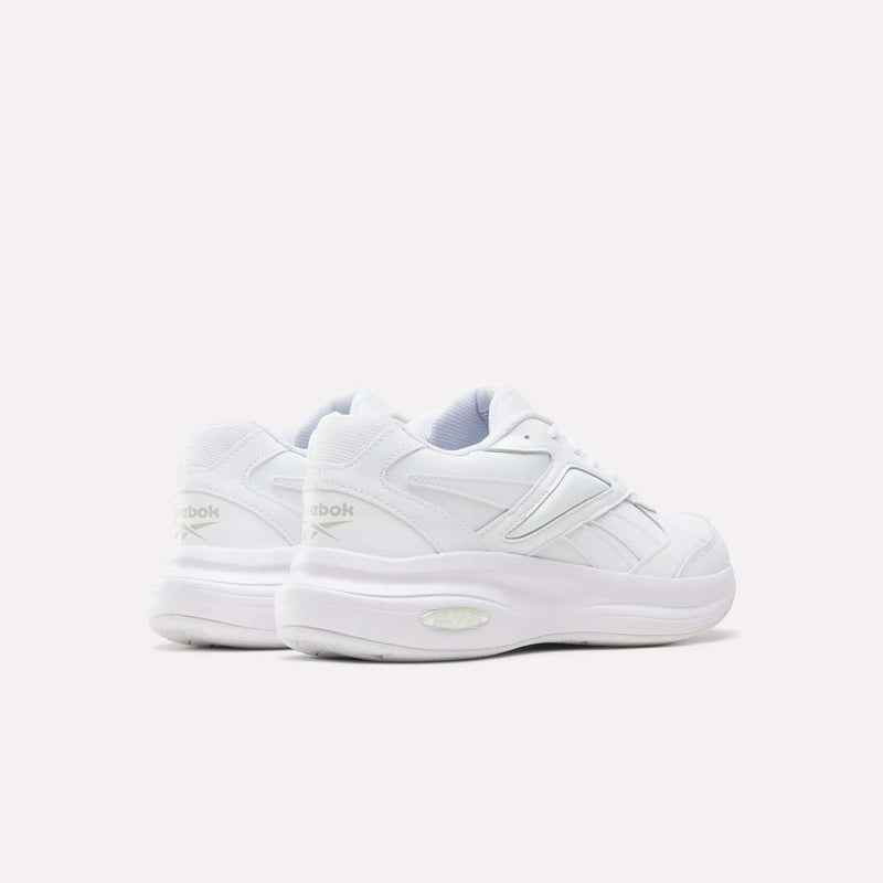 A pair of Reebok Men’s DMX Comfort+ Walk Ultra shoes in white, featuring thick soles and DMX Comfort+ cushioning, shown from the back and side angles against a plain light background.
