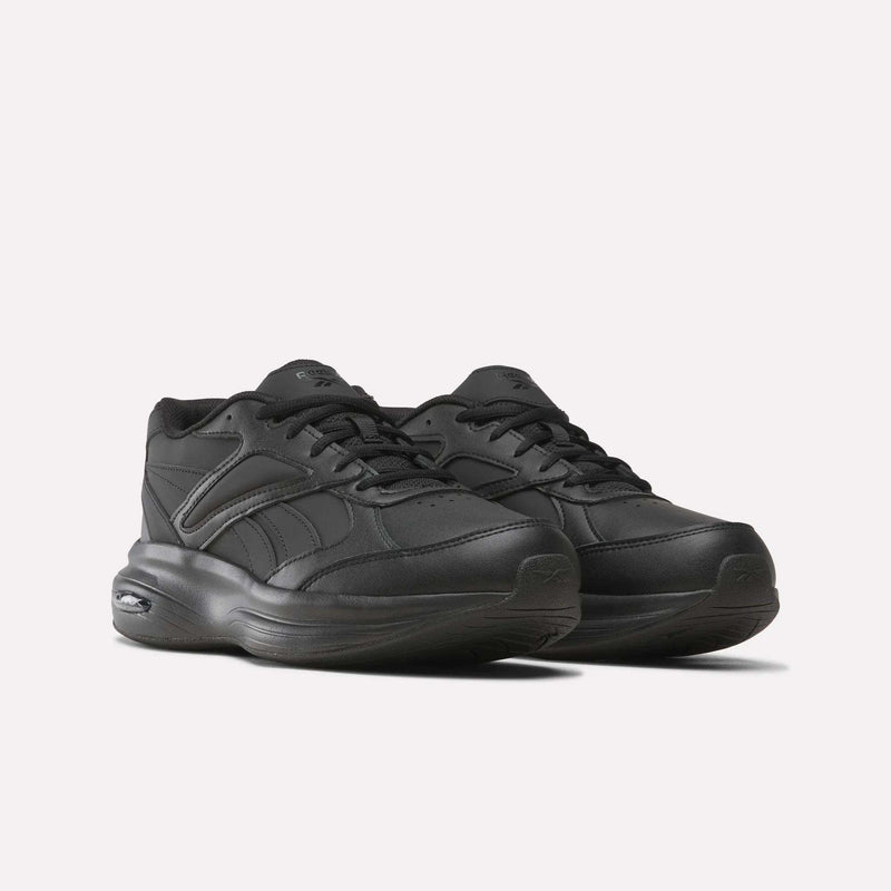 A pair of black Reebok Men’s DMX Comfort+ Walk Ultra Shoes with thick soles, lace-up fronts, and subtle stitched detailing are displayed against a plain white background. These athletic sneakers feature DMX Comfort+ cushioning for enhanced support and all-day comfort.