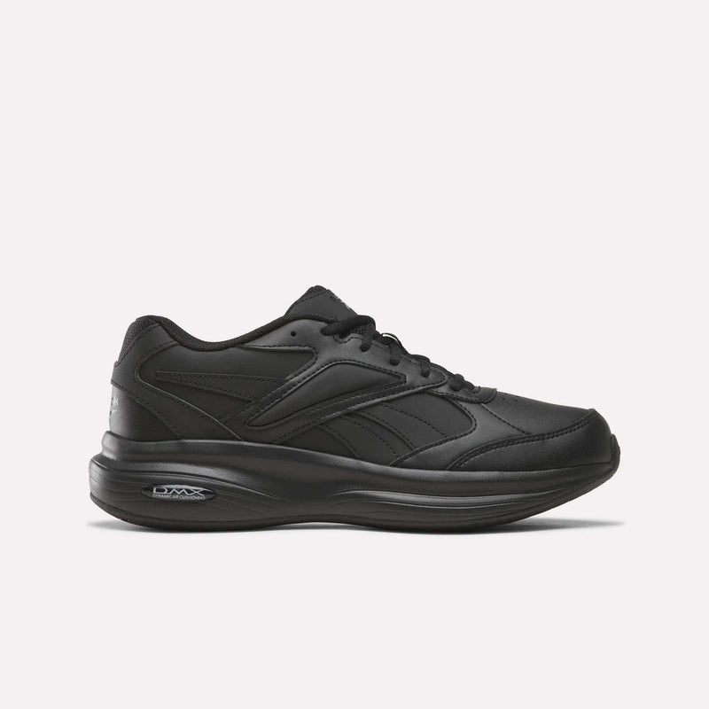 A men’s walking shoe from Reebok, the DMX Comfort+ Walk Ultra, in an all-black colorway (Aha - Black/Black/Black), featuring a low-top athletic design, lace-up closure, and a thick cushioned sole enhanced with DMX Comfort+ cushioning. The shoe is displayed against a plain, light-colored background to highlight its sleek appearance.