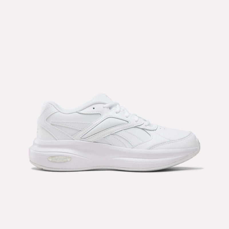 The Reebok Women’s DMX Comfort + Walk Ultra Shoes in Aha - White/White/White feature a low-top profile, lace-up closure, subtle stitching accents, and a thick cushioned sole with DMX Comfort+ cushioning—making them ideal women’s walking shoes—shown here on a plain white background.