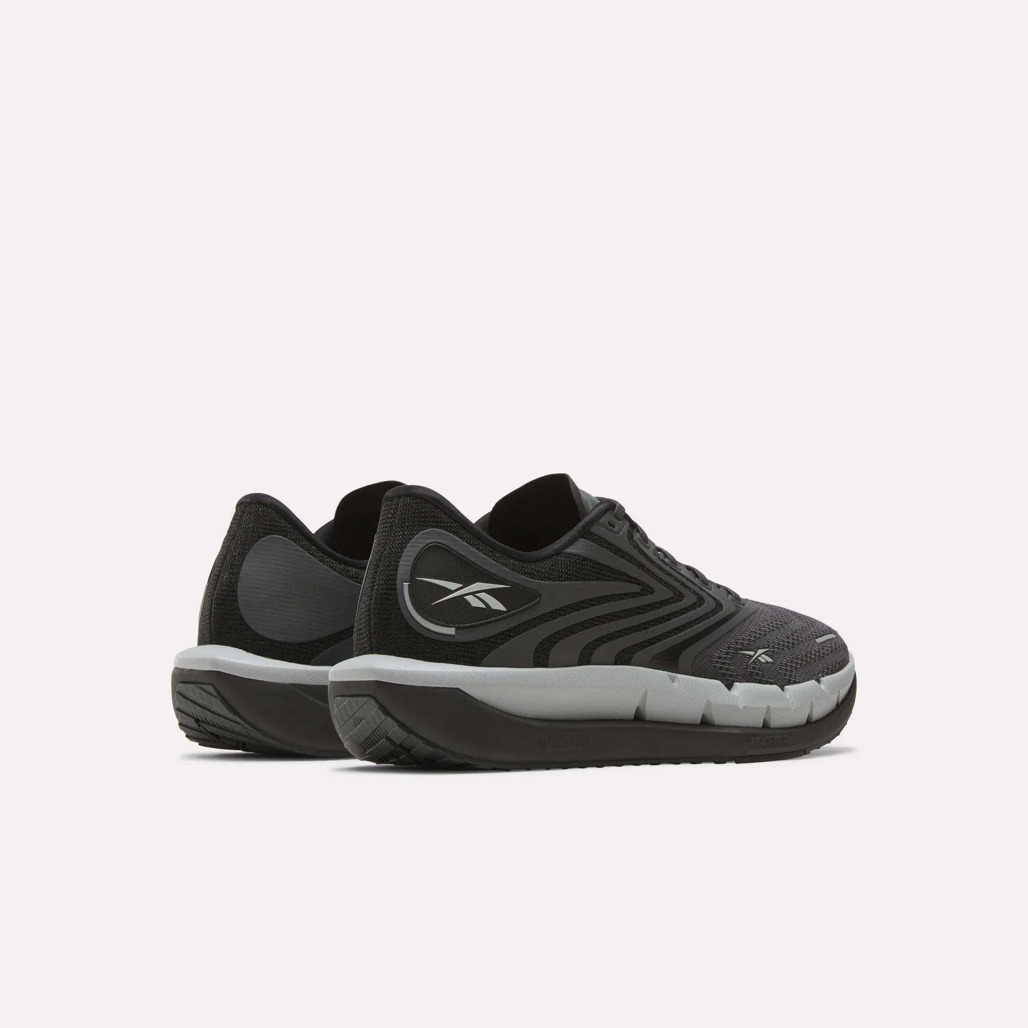 A pair of Reebok Men's FloatZig Tread Running Shoes in black and gray with white soles and a cushioned midsole are placed side by side on a light background—ideal for treadmill workouts.
