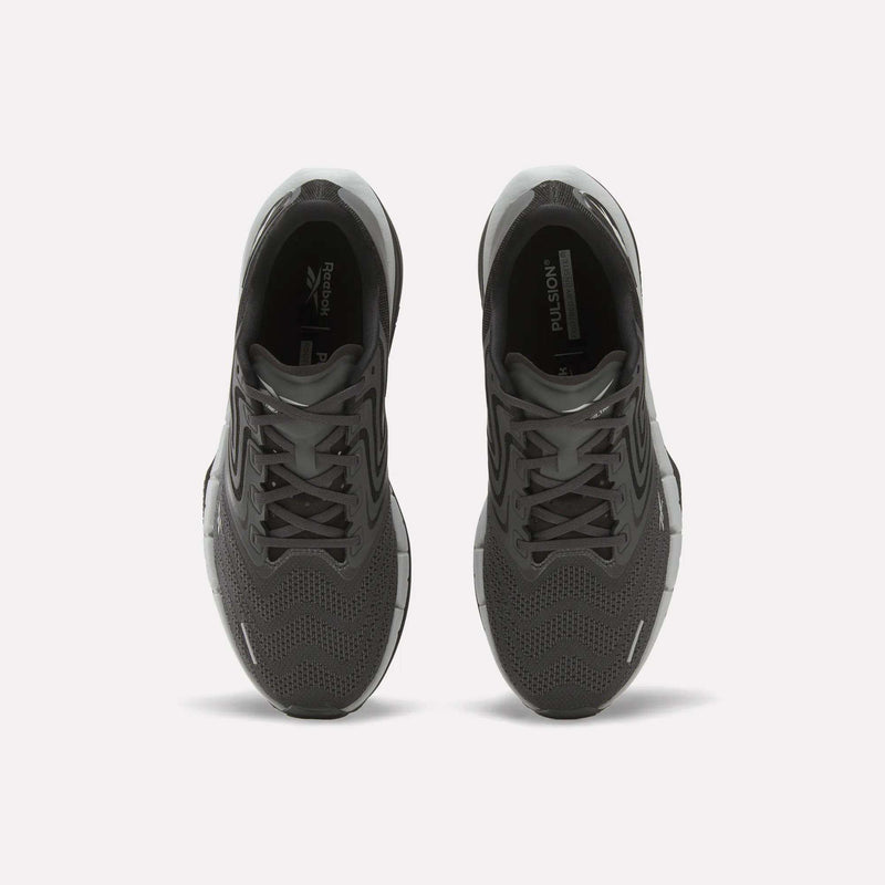 A pair of Men’s FloatZig Tread Running Shoes by Reebok in black, seen from above with laces, mesh uppers, and branded tongue. Cushioned midsoles make them ideal for treadmill workouts. Placed side by side on a plain white background.