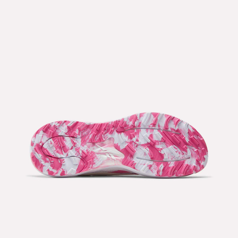 The image displays the sole of Reebok Nano Golf Shoes, featuring a vibrant pink, white, and light gray marbled pattern. The tread has various grooves and curved lines for traction. The background is plain and light-colored.