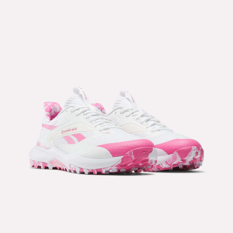 A pair of Reebok Nano Golf Shoes in white with bright pink accents and soles, featuring a lightweight FlexWeave upper and patterned heel and outsole, displayed against a plain white background.