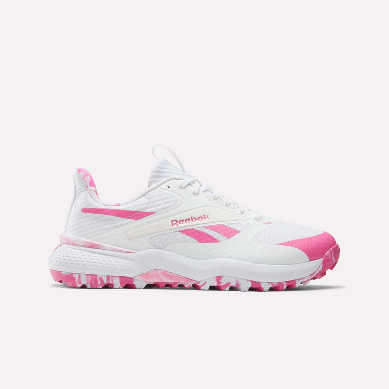 The Reebok Nano Golf Shoes are white athletic shoes with pink accents, featuring a lightweight FlexWeave upper and a pink-and-white camo pattern on the sole and heel tab for style and breathability.
