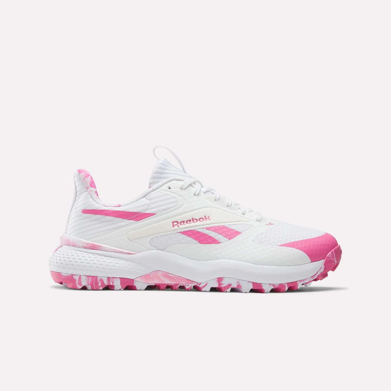 The Reebok Nano Golf Shoes are white athletic shoes with pink accents, featuring a lightweight FlexWeave upper and a pink-and-white camo pattern on the sole and heel tab for style and breathability.