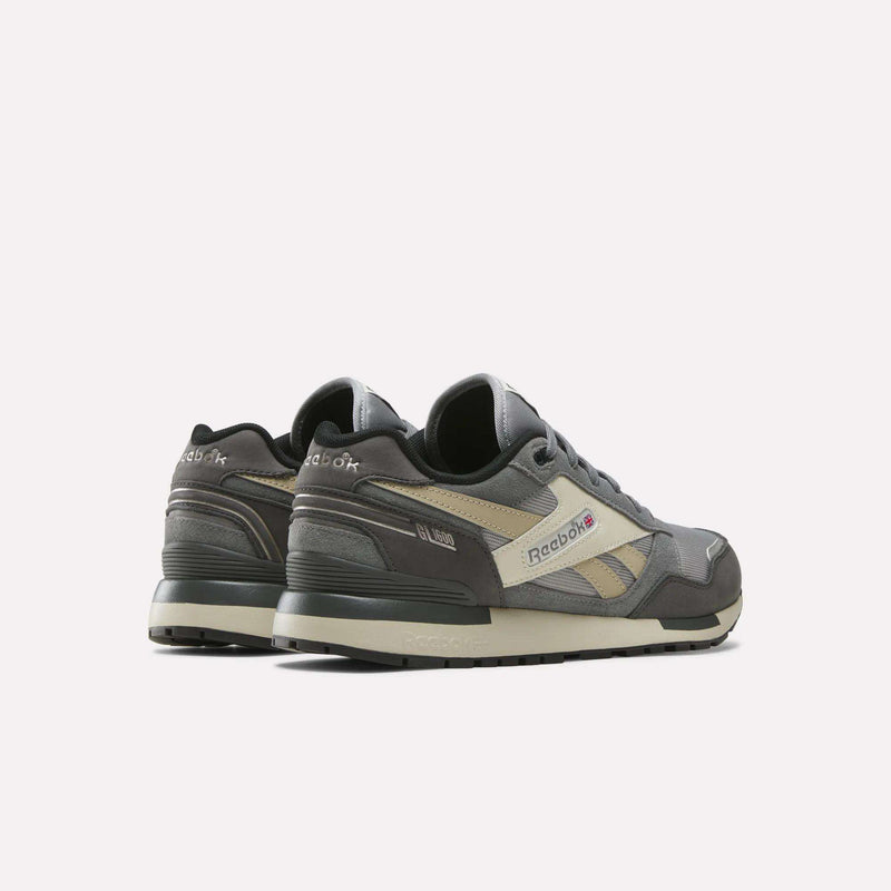 A pair of Men's GL1600 Shoes by Reebok in gray with beige and black accents, featuring a suede upper, are showcased from the back and side views against a plain white background.