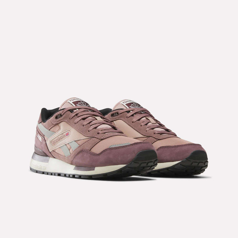 A pair of Reebok Men’s GL1600 Shoes in mauve and gray suede, featuring white midsoles, black outsoles, and Reebok branding on the sides and tongues, displayed against a plain white background.