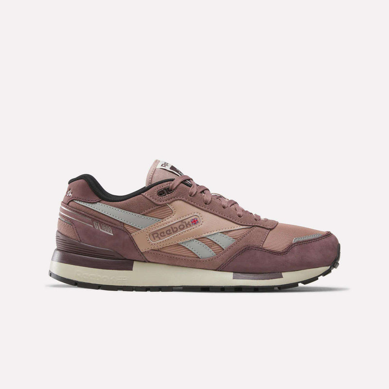 A pair of Men’s GL1600 Shoes by Reebok in Dark Cocoa, New Grey 2, and Light Cocoa colorway is showcased against a plain white background. Featuring grey accents, the signature side logo, black interior lining, and a durable rubber sole, these stylish suede sneakers are designed for both comfort and enduring appeal.