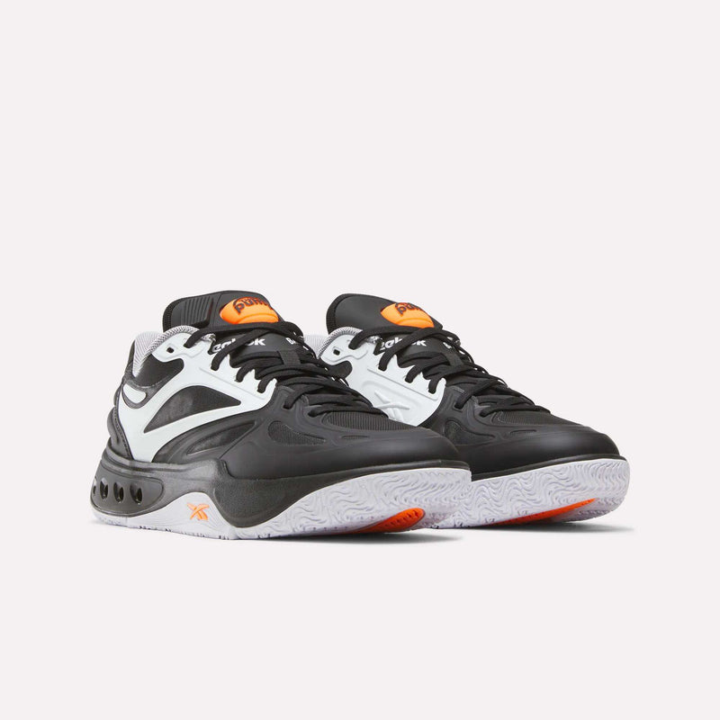 A pair of Reebok Engine A Pump Shoes in black, white, and orange with a chunky sole and curved design lines, featuring Pump technology for enhanced fit and support, displayed against a plain white background.