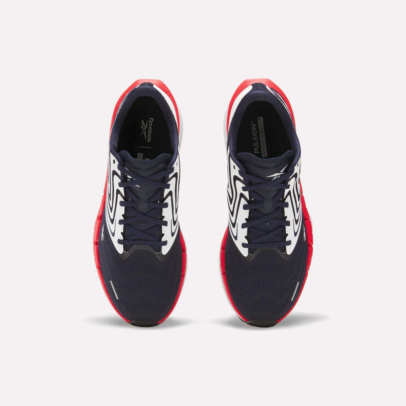 The Reebok Men's FloatZig Tread Running Shoes feature navy blue mesh toes, white patterned sides, and bright red soles—ideal for treadmill workouts. Shown from above against a plain white background.