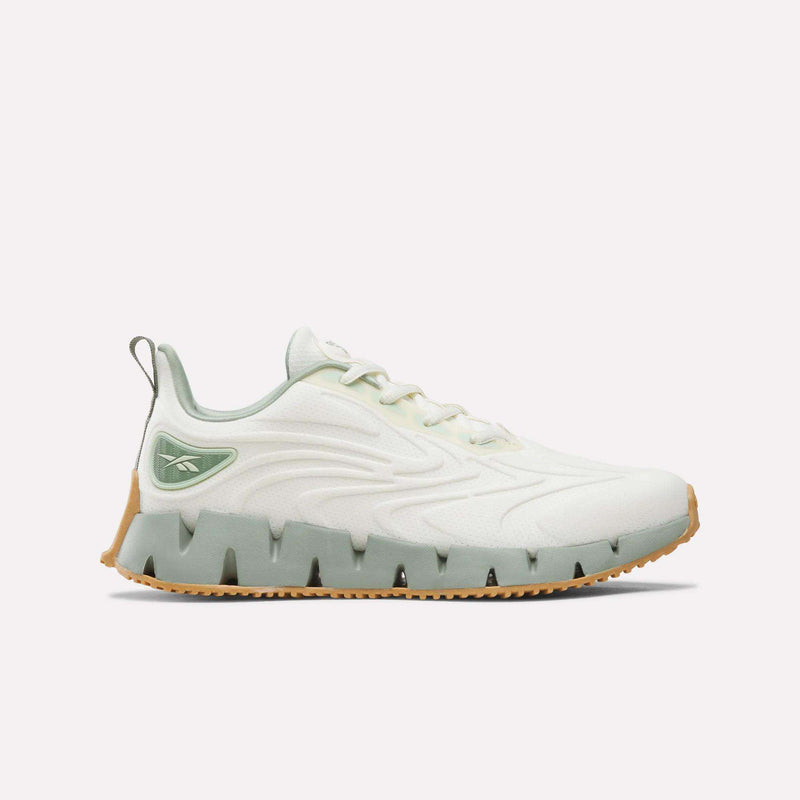 Off-white Women’s Zig Futaura 1.0 Shoes featuring a green-tinted, zigzag-shaped FuelFoam midsole and a gum rubber outsole.