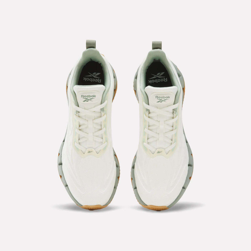 Top-down view of Women’s Zig Futaura 1.0 shoes by Reebok, featuring a white design with sage green accents and a zigzag-patterned FuelFoam midsole.