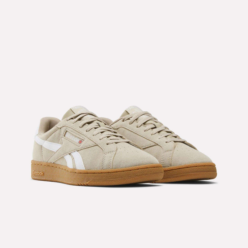 A pair of Men’s Club C Grounds UK 1.0 Shoes by Reebok, crafted in soft beige suede with signature white stripes and gum soles, are displayed side by side on a plain white background—a classic nod to Reebok’s heritage.